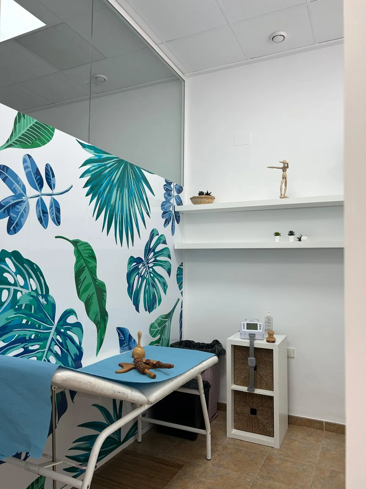 Cabina de tratamiento con pared de hojas tropicales y camilla